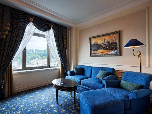 a living room with a blue couch and a window at Fairmont Grand Hotel Kyiv in Kyiv