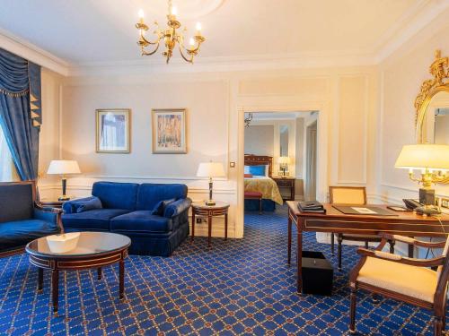 a living room with a blue couch and a room with a bed at Fairmont Grand Hotel Kyiv in Kyiv
