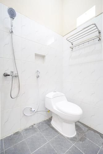 a white bathroom with a toilet and a shower at Omah Ati Guesthouse Syariah in Jarakan