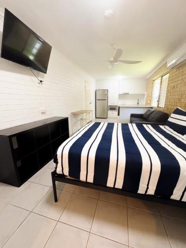 a bedroom with a bed with a black and white striped comforter at Motel Sunshine Coast in Caloundra