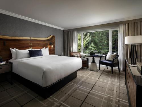 a bedroom with a large white bed and a desk at Fairmont Chateau Whistler in Whistler