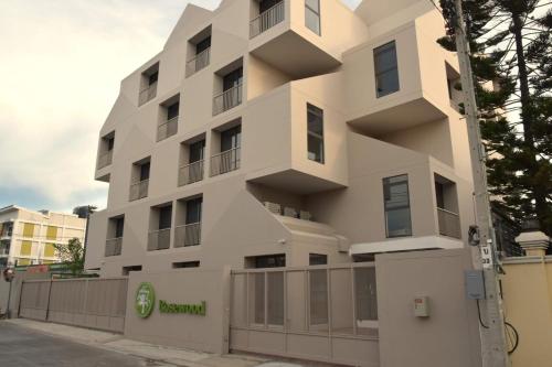 a white building with a fence in front of it at Rosewood Sridan in Ban Khlong Samrong