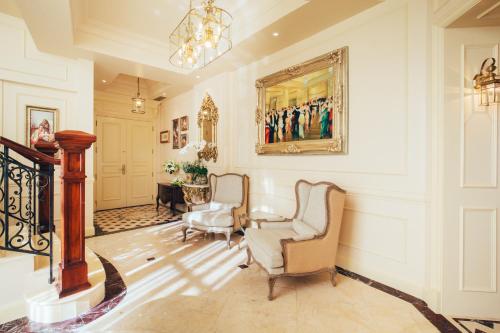 a living room with two chairs and a painting on the wall at The IMPERIAL Vung Tau Hotel in Vung Tau