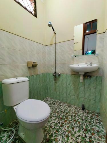 a bathroom with a toilet and a sink at Abadi Kos Harian in Ngabean