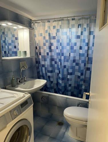 a bathroom with a toilet sink and a washing machine at St Andrews Seafront Appartement in Agios Andreas