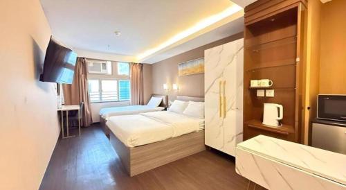 a hotel room with two beds and a television at Sunny Day Hotel in Hong Kong