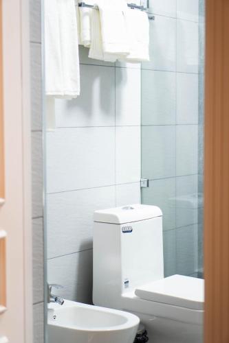a white bathroom with a toilet and a sink at Air Plaza in Samarkand