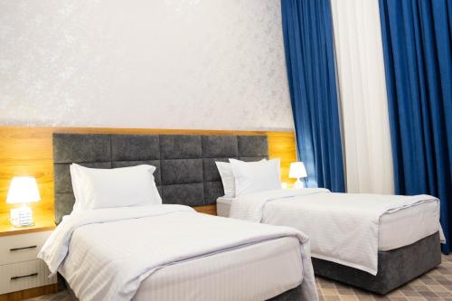 two beds in a hotel room with blue curtains at Air Plaza in Samarkand