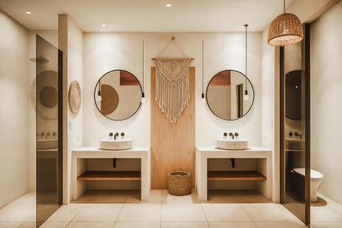 a bathroom with two sinks and two mirrors at Kavo Maison Surf & Yoga Camp in Munggu