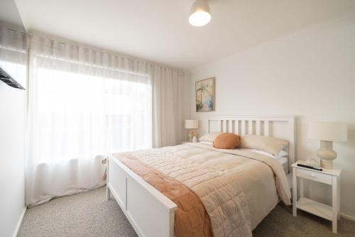 Un dormitorio blanco con una cama y una ventana. en Seafoam Beach Retreat, en Surf Beach