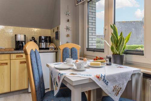 a kitchen with a white table and chairs and a table and chairsktop at Ferienwohnung KUMM RIN - Oase an der Nordsee in Carolinensiel
