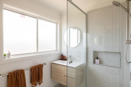 Un baño con ducha, lavabo y espejo. en Seafoam Beach Retreat, en Surf Beach