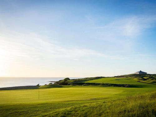 a green golf course with the ocean in the background at Fairmont St Andrews, Scotland in St. Andrews