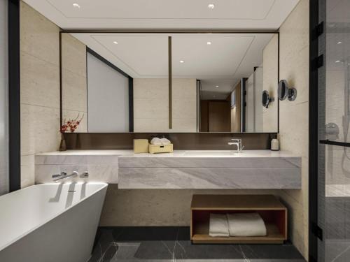a bathroom with a tub and a large mirror at Swissotel Beijing Hong Kong Macau Center - 1 min to subway in Beijing