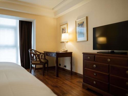 a hotel room with a desk with a television and a bed at Swissotel Lima in Lima