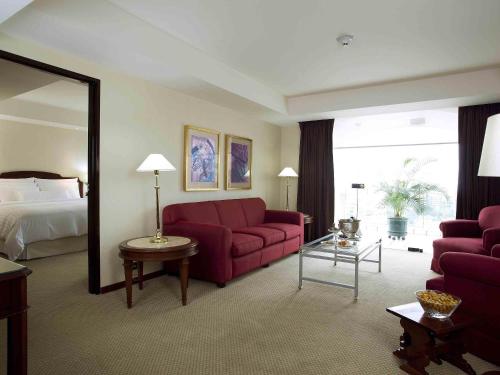 a living room with a red couch and a bed at Swissotel Lima in Lima