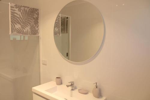 a white bathroom with a sink and a mirror at Doc's Place at Crescent Head in Crescent Head