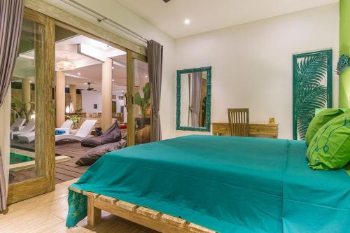 a bedroom with a blue bed and a living room at Villa Josefine, 5 Bedroom pool, rooftop, pool table in Seminyak