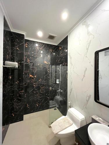 a bathroom with a toilet and a glass shower at Alloro Boutique Hotel Pacitan in Pacitan