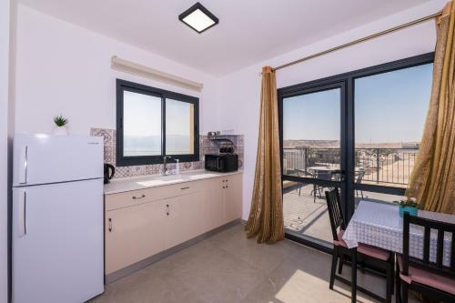 a kitchen with a refrigerator and a large window at זוהר במדבר ים המלח in Neve Zohar