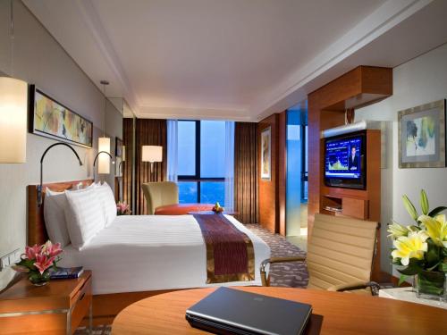 a hotel room with a bed and a desk with a laptop at Swissotel Foshan, Guangdong - Free shuttle to Canton Fair in Foshan
