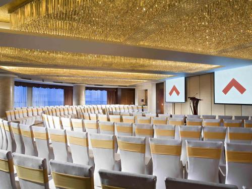a conference room with white chairs and a gold ceiling at Swissotel Foshan, Guangdong - Free shuttle to Canton Fair in Foshan