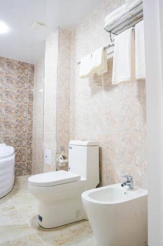 a white bathroom with a toilet and a sink at Air Plaza in Samarkand