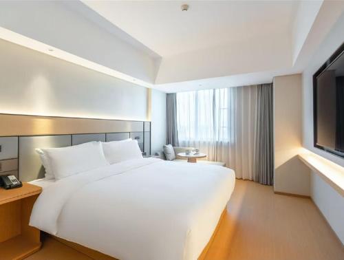 a large white bed in a hotel room with a television at Ji Hotel Guangzhou Zhujiang New Town in Guangzhou