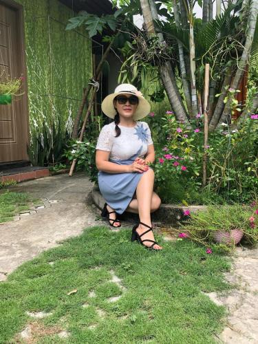 a woman in a hat sitting on a bench at Khang Bảo Viên in Củ Chi