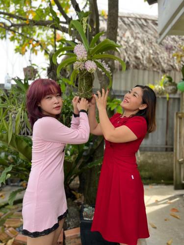 two women are standing next to each other holding a plant at Khang Bảo Viên in Củ Chi