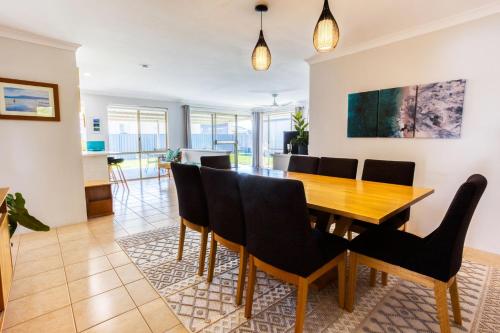 a dining room and living room with a wooden table and chairs at Marine Holiday Home - Geographe in Geographe