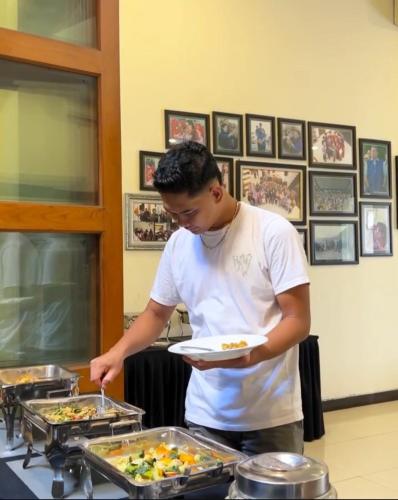 Een man houdt een bord eten vast. bij Alloro Boutique Hotel Pacitan in Pacitan