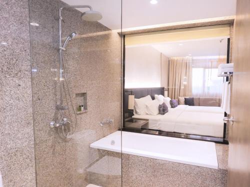 a bathroom with a shower and a bed and a mirror at Sima Thani Hotel in Nakhon Ratchasima