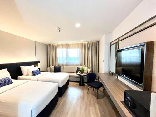 a hotel room with two beds and a flat screen tv at Sima Thani Hotel in Nakhon Ratchasima
