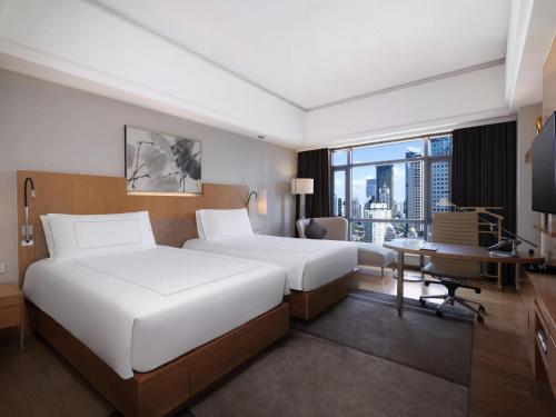 a hotel room with two beds and a desk at Swissôtel Grand Shanghai - Stroll down West Nanjing Road and soak in downtown Shanghai vibrancy in Shanghai