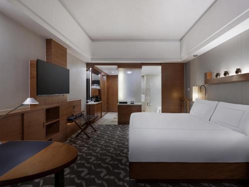 a bedroom with a bed and a desk and a television at Swissôtel Grand Shanghai - Stroll down West Nanjing Road and soak in downtown Shanghai vibrancy in Shanghai