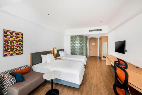a hotel room with a white bed and a couch at Holiday Inn Express Haikou West Coast by IHG in Haikou