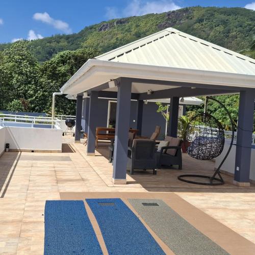 a pavilion with awning on a patio with a table and chairs at Harmony Self-Catering Apartments in Beau Vallon
