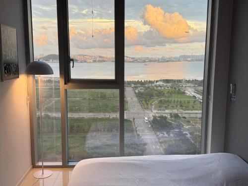 a bedroom with a large window with a view of the water at Grape Residence Hotel in Incheon