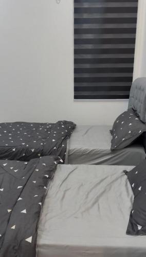 a bed with black and white pillows and a window at Ali Homestay Jeli in Jeli
