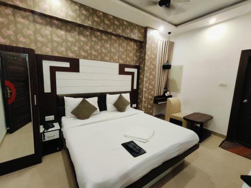 a bedroom with a large white bed with a remote control on it at Hind palace in Lucknow