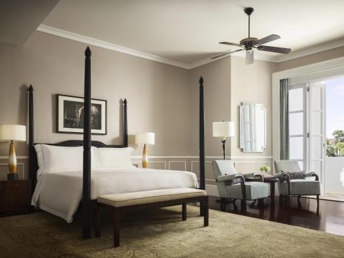 a bedroom with a bed and a ceiling fan at Raffles Grand Hotel d'Angkor in Siem Reap