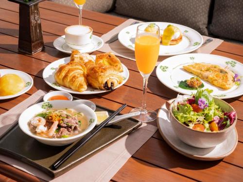 a wooden table topped with plates of food and drinks at Raffles Grand Hotel d'Angkor in Siem Reap