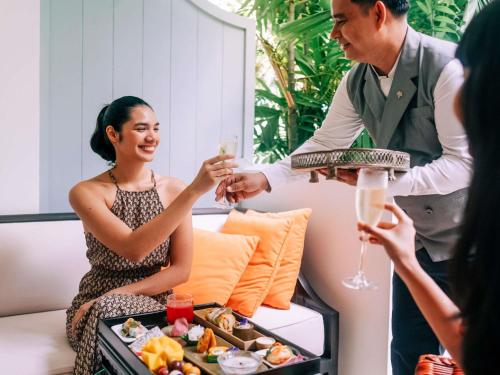 a man serving a woman a plate of food at Raffles Grand Hotel d'Angkor in Siem Reap