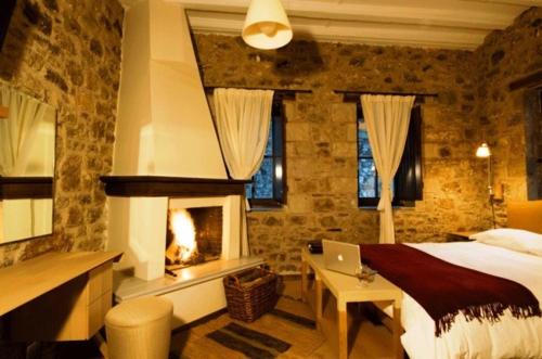 1 dormitorio con chimenea, 1 cama y ordenador portátil en Guesthouse Theonimfi, en Dhimitsana