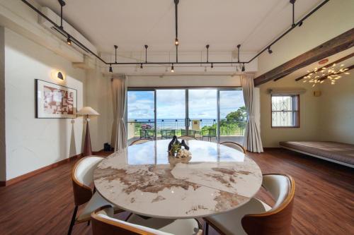 a room with a table and chairs and a large window at クリスタル別荘南城 in Nanjo