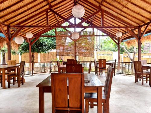 a restaurant with tables and chairs and a wooden roof at Oasi Bungalow Gili Air in Gili Islands