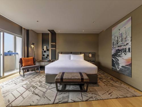 a bedroom with a bed and a desk and a chair at Swissotel The Stamford Singapore in Singapore