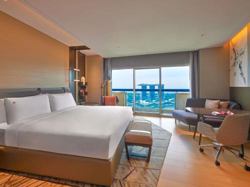 a bedroom with a large bed and a living room at Swissotel The Stamford Singapore in Singapore