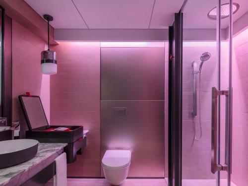 a bathroom with a shower and a toilet and a sink at Swissotel The Stamford Singapore in Singapore